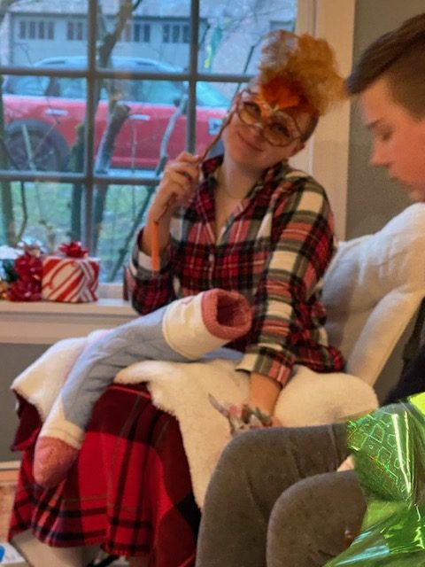 Teenage girl opening presents in a holiday setting.