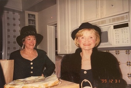 Pam and a friend dressed in black formalwear with hats